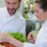 Deux chefs regardent la qualité des salades et tomates dans une cagette