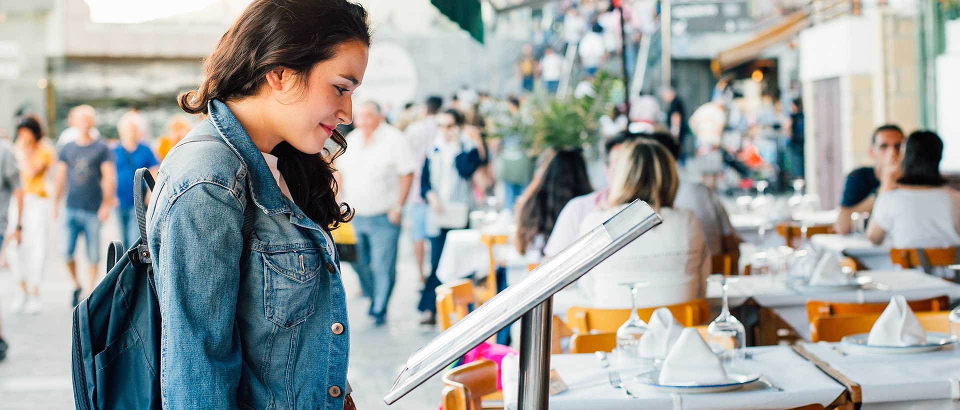 Une jeune femme regarde le menu devant un restaurant